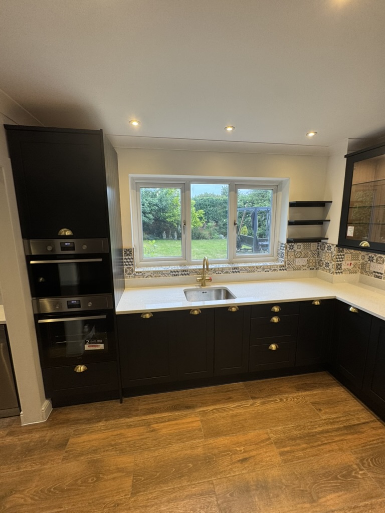 Completed kitchen with black shaker cabinets, brass handles and patterned splashback